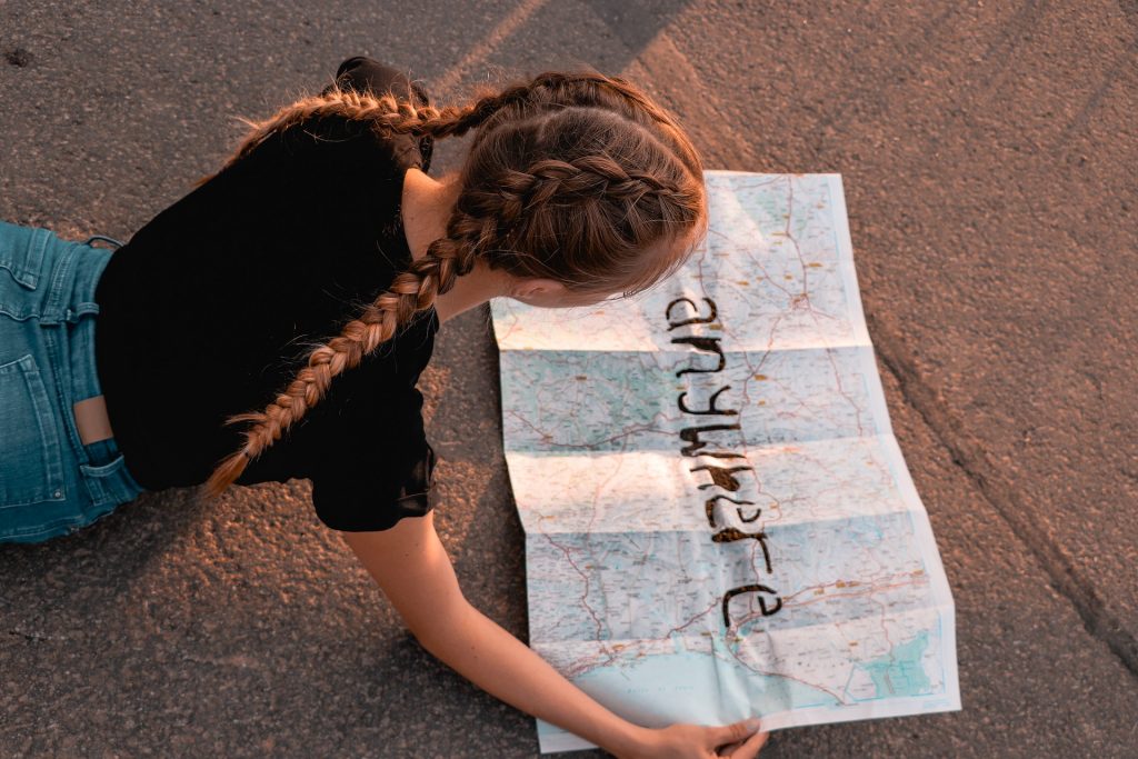 Girl looking at a map while lying on the street