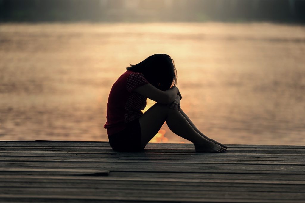 Sad girl sitting at the lake